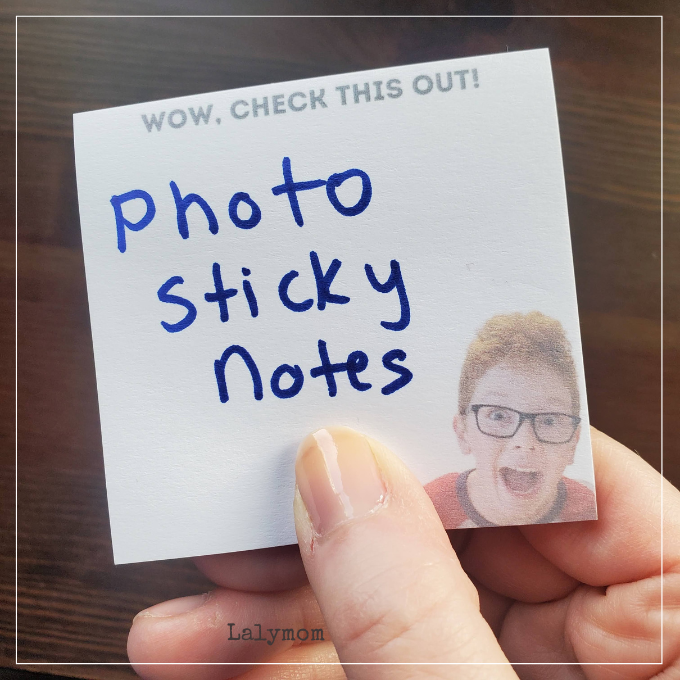 Photo of a hand holding a post it note. Post it has a photo of a child printed on it with printed text that reads "Wow Check this out!" Hand writing on the note says Photo Sticky Notes.